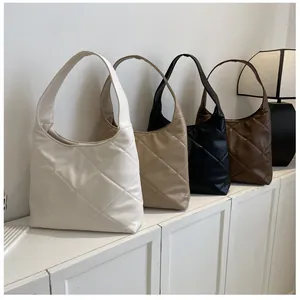 Quilted tote bags shown in white, khaki, black and brown on a modern display shelf