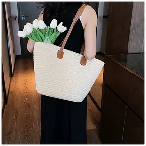 Detail of large straw tote bag featuring brown leather straps and woven texture