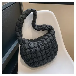 Close-up of black quilted puffer shoulder bag with bubble texture on a modern chair