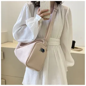Gros plan du sac bandoulière en cuir rose pâle avec boucles argentées sur modèle