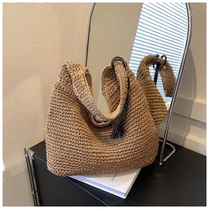 Detail view of the hand-woven straw bag texture with elegant tassel charm and lining