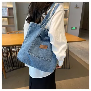 Detailed back view of a large blue denim tote bag worn by a model in a stylish interior