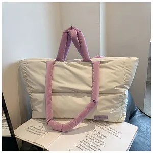 Dettaglio della borsa tote trapuntata panna e viola appoggiata su un libro di design