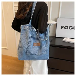 Detailed back view of a blue denim tote bag worn on shoulder in modern interior setting