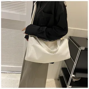 Sac fourre-tout blanc avec texture crocodile porté par un mannequin dans un salon