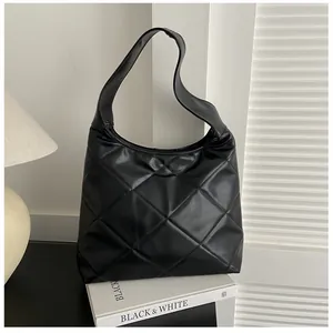Detailed view of black quilted rhombus hobo bag on books with matte leather texture