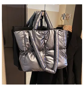 Detailed macro view of quilted silver metallic puffer tote bag with wide shoulder strap