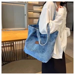Detail of blue denim tote bag with leather patch pocket in a library setting