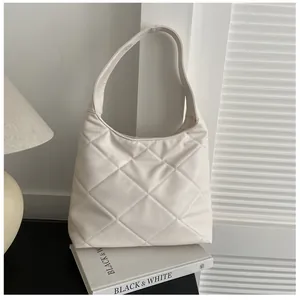 Macro detail of large diamond quilting on cream faux leather hobo shoulder bag