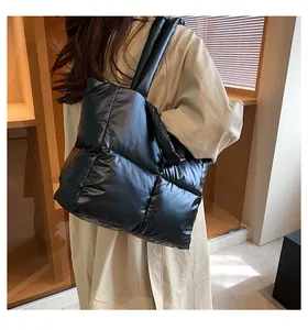 Close-up of black quilted down tote bag with wide shoulder strap worn by a model