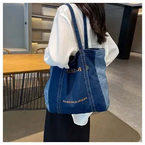 Close-up of dual-tone denim tote bag featuring yellow embroidery and spacious design