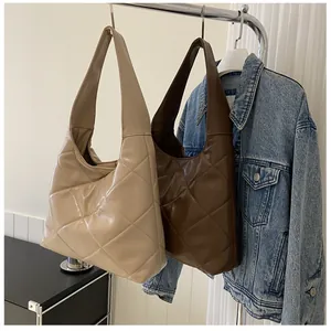 Close-up of beige and dark brown quilted tote bags in a stylish indoor setting