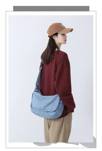 Detail of light blue denim tote bag showing wide adjustable strap and flap closure