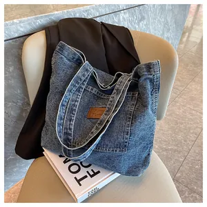 Close-up of vintage blue denim tote bag with leather patch on a beige fabric chair