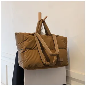 Dettaglio di una borsa tote trapuntata marrone con etichetta in pelle su un gancio
