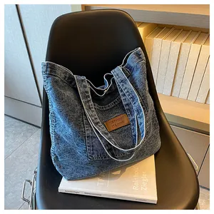 Detailed macro of washed blue denim tote bag texture with brown leather logo patch