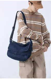 Detail of blue denim messenger bag with wide adjustable strap and contrast stitching