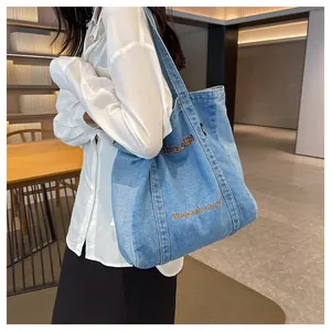 Detailed close-up of light blue denim tote bag with orange WISDOPA letter embroidery