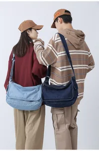 Detail view of large denim messenger bags in light and dark blue with adjustable straps