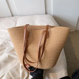 Large woven straw tote bag with dark brown leather handles for beach or summer vacation
