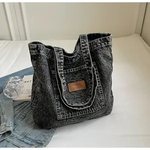 Close-up of washed denim tote bag with leather logo patch and durable wide handles