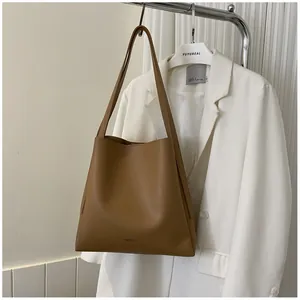 Detail of caramel brown matte leather tote bag featuring a minimalist AIBEIDA logo imprint