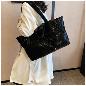 Dettaglio di una grande borsa trapuntata nera lucida con etichetta in pelle su una modella