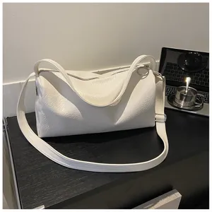 Vue macro de la texture du cuir blanc et des boucles argentées de ce sac à bandoulière