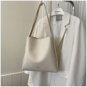 Detail of minimalist beige tote bag with brand logo shown against white suit background