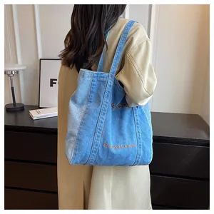 Detail shot of the blue denim tote bag featuring white Wisdora Jeans embroidery