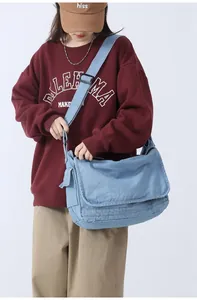 Side view of large light blue denim crossbody messenger bag with adjustable strap