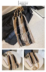 Detail of bohemian woven straw bag with black and white stripes and long fringe tassels
