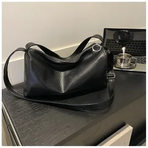 Détail d'un sac à bandoulière en cuir noir gaufré avec anneau de fermeture argenté