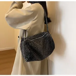 Detailed view of large washed denim shoulder bag with quilted texture and metal zipper