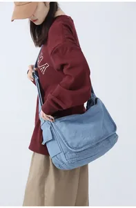 Detail view of the light blue denim messenger bag with flap closure and side pockets