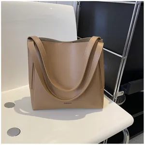 Detail showing matte khaki leather texture and slim handles of the bucket tote bag