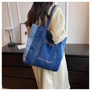 Detail of blue denim tote bag with contrast stitching and shoulder strap view