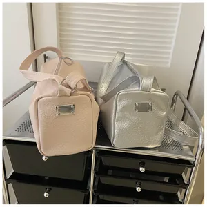 Détail de sacs fourre-tout cylindriques rose et argent en cuir craquelé avec anneau métal