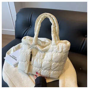 Detail of off-white quilted tote bag set with a small detachable pouch on a leather sofa