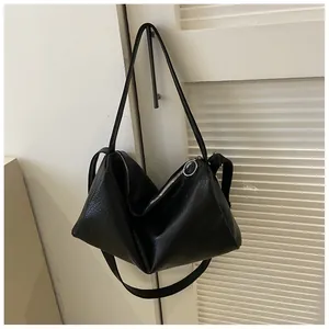 Détail de la texture cuir noir et fermeture éclair argentée sur un sac à bandoulière