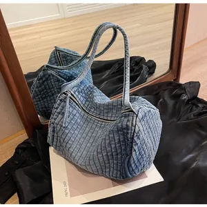 Detail of blue washed denim shoulder bag with vertical quilted texture and zipper