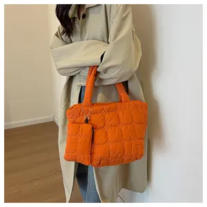 Close-up of bright orange quilted tote bag with matching small pendant pouch and chain