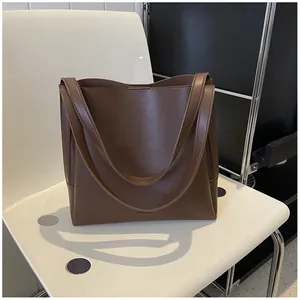 Detail of embossed brand logo on vintage dark brown PU leather tote bag surface