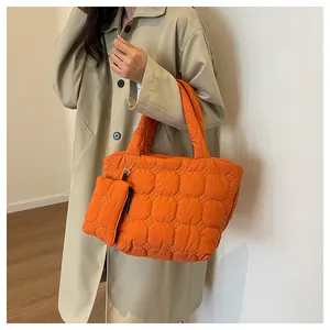 Detail of bright orange quilted tote bag with matching mini zip pouch on shoulder
