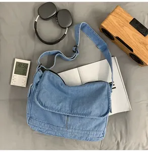 Blue denim messenger bag with adjustable strap shown in a creative lifestyle setting