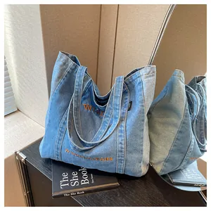 Detail of blue denim tote bag with orange Wisdom embroidery and sturdy top handles