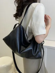 Sac fourre-tout noir minimaliste en cuir texturé porté par un mannequin chic