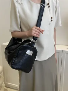 Sac à bandoulière cylindrique noir minimaliste en cuir craquelé avec détails argentés