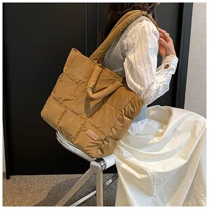 Detailweergave van grote gewatteerde puffer tote tas met modepatch en schouderband