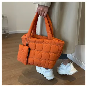 Detail of quilted puffer tote bag in bright orange with matching mini side pouch